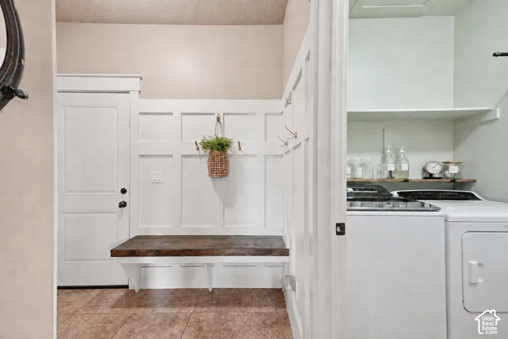 Mudroom with a built-in bench, paneling with coat hooks, and durable tile flooring
