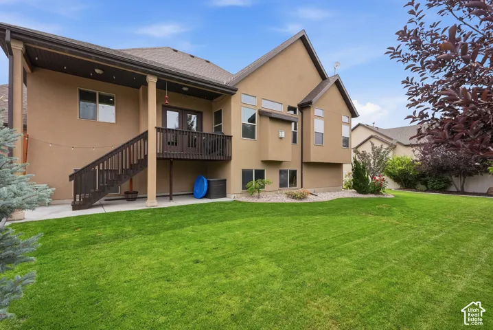 Stucco exterior with a multi-level roofline, covered patio, and wood deck