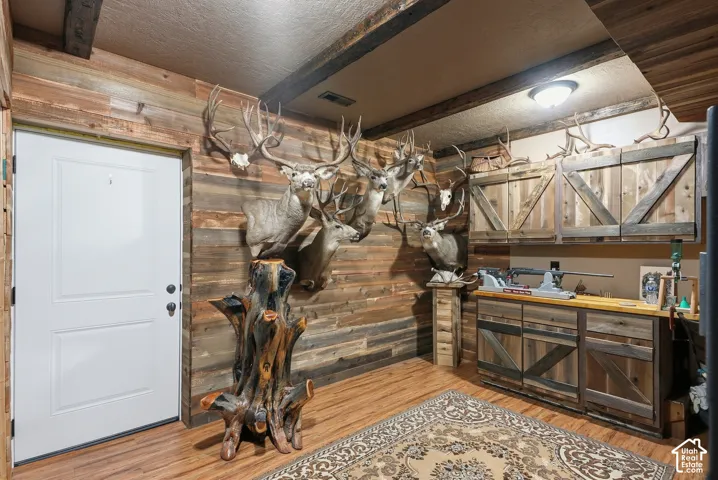 Reclaimed wood-finish wall paneling, wood-finish flooring, wood ceiling beams, and barn-door style cabinetry with a built-in counter