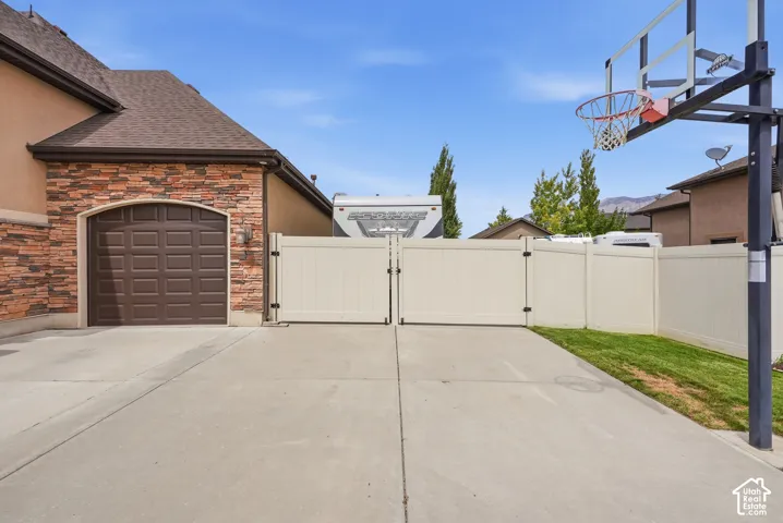 Expansive concrete driveway with a basketball hoop, leading to a garage with a paneled door
