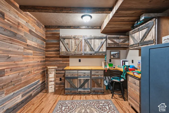 Custom wood-paneled walls, built-in cabinetry with diagonal bracing, butcher-block countertops, and wood-finish flooring
