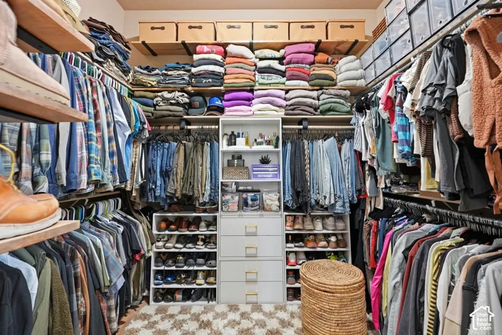 Walk-in closet featuring extensive built-in shelving, multiple hanging rods, and a central dresser unit with drawers