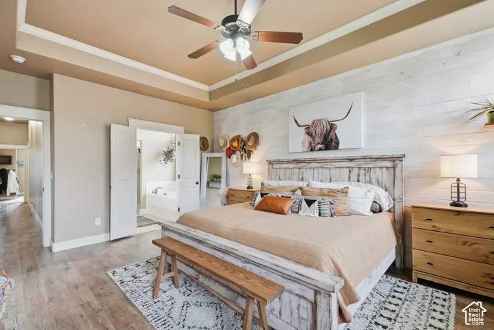 Wood-finish flooring, recessed ceiling with crown molding, double doors, and a decorative accent wall