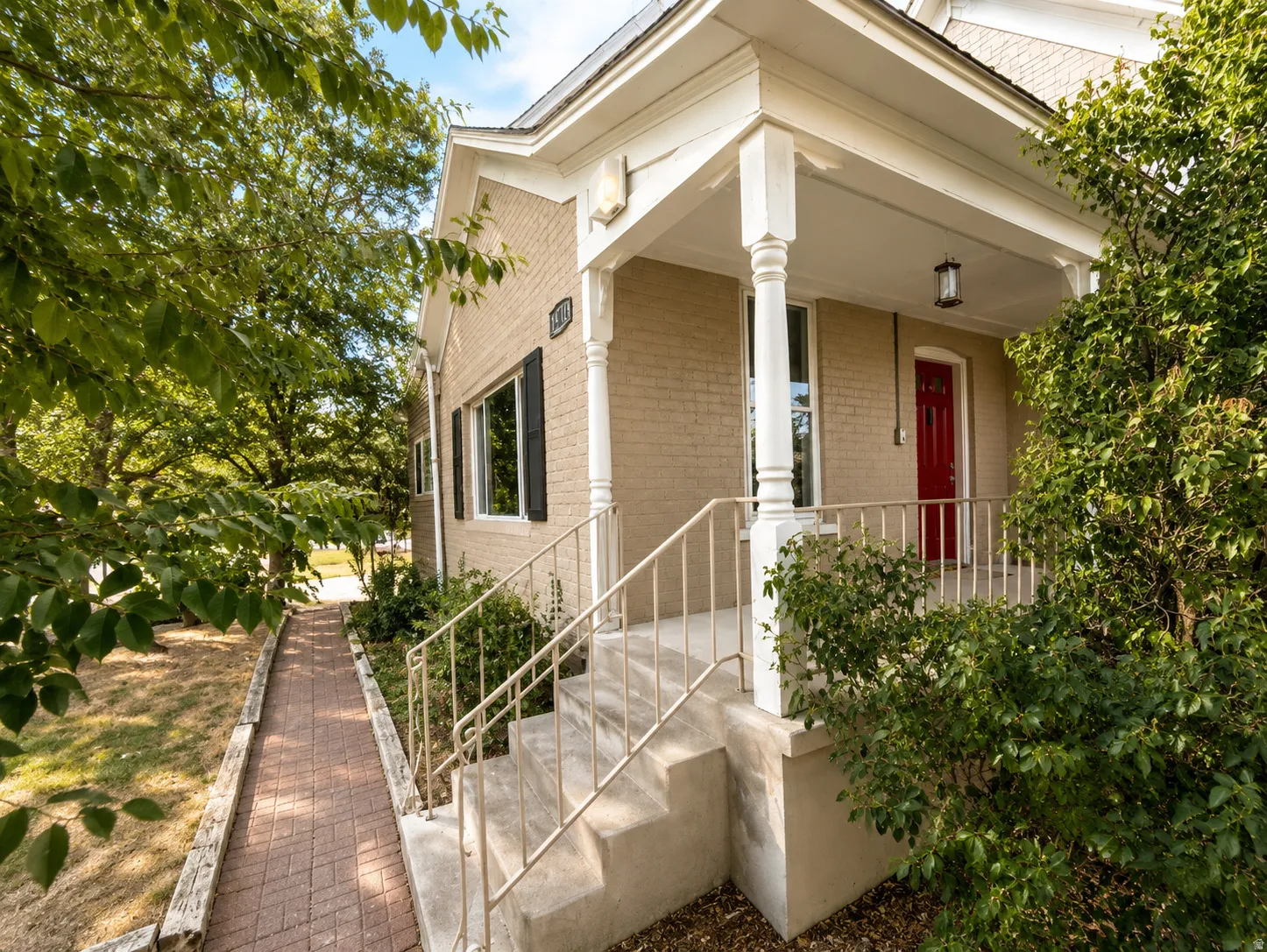 Brick exterior with a covered porch, white columns, and a red entry door