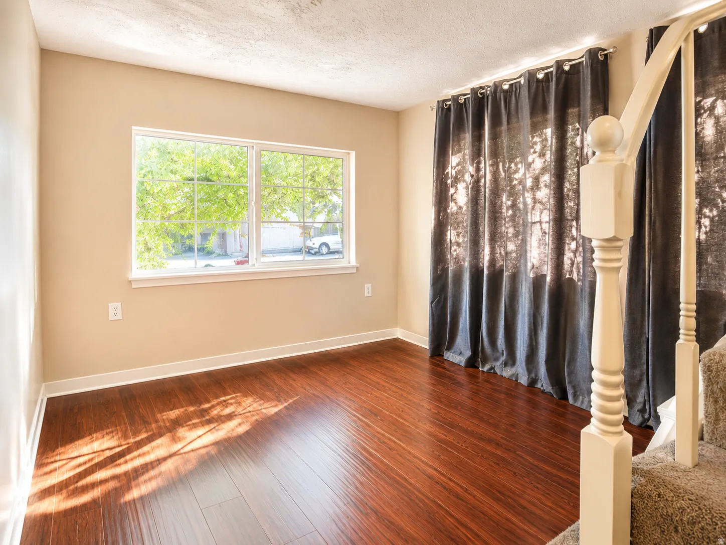 Hardwood-style flooring throughout, neutral tone walls, and a white-trimmed window