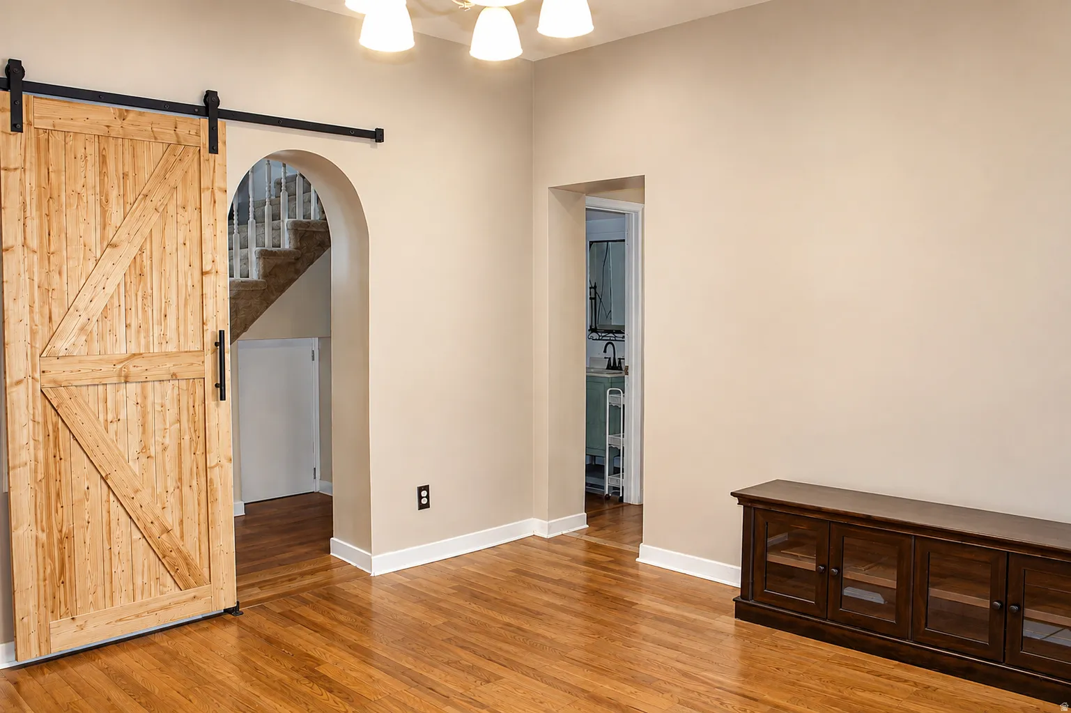 Hardwood flooring throughout, with a natural wood barn door on a black metal track