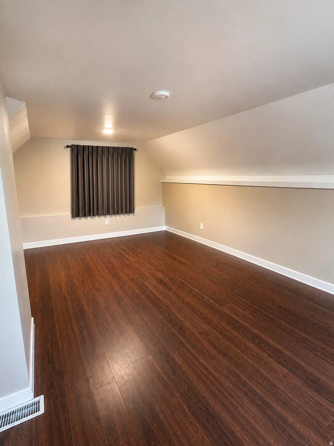 Spacious room featuring wood-finish flooring, recessed lighting, and sloped ceilings