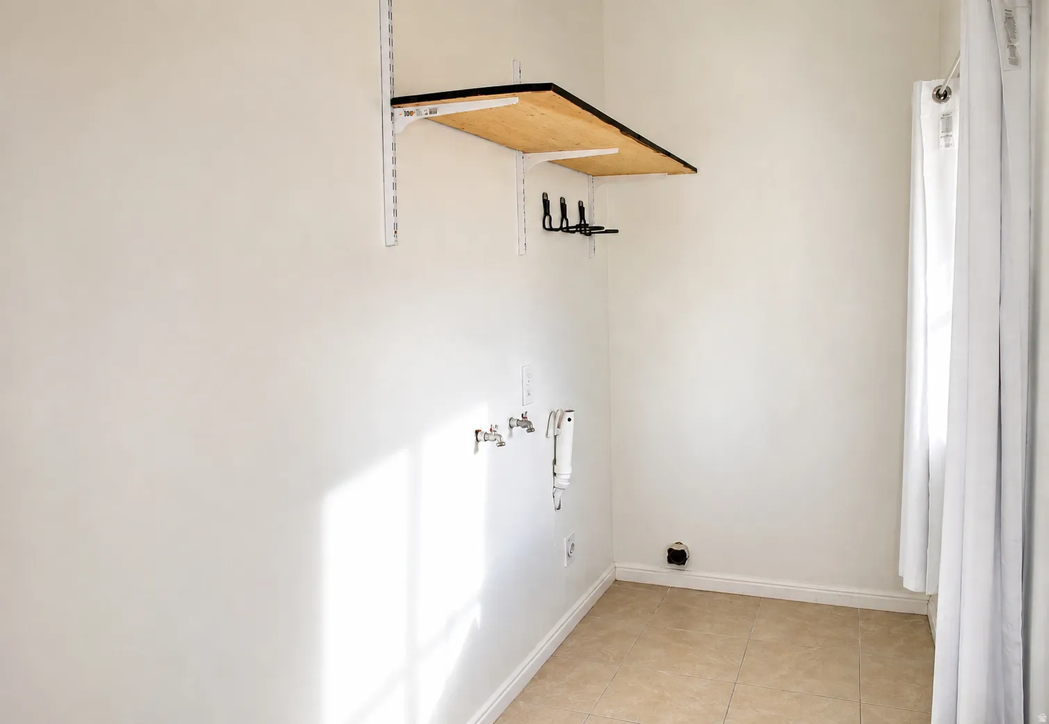 Laundry area with tile flooring and a built-in wood-finish shelf