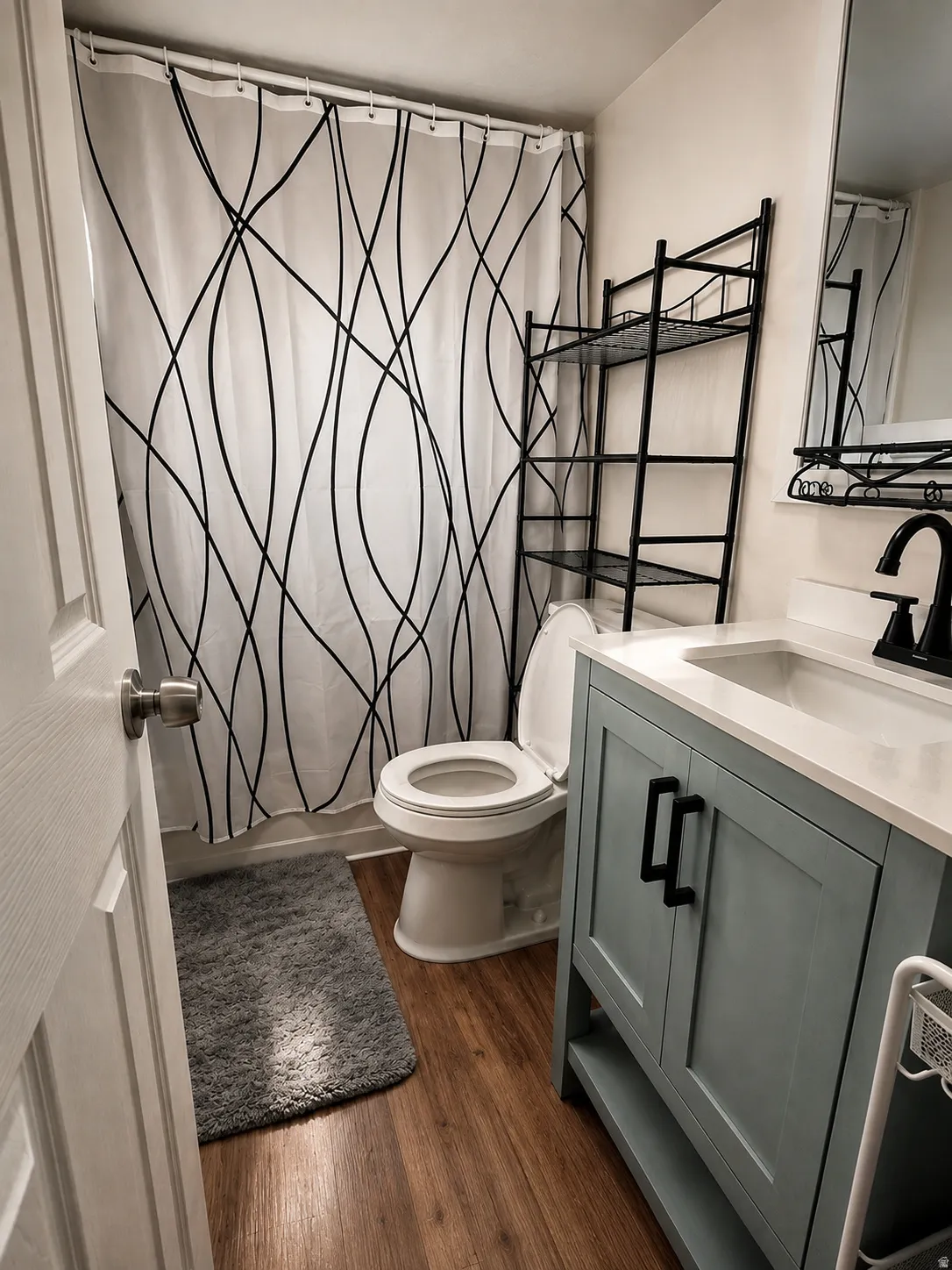 Modern bathroom featuring a single vanity with a light blue cabinet, a white countertop, and a black faucet