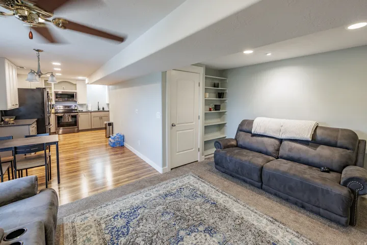 Open-concept living area featuring a kitchen with stainless steel appliances, wood-finish flooring, and recessed lighting