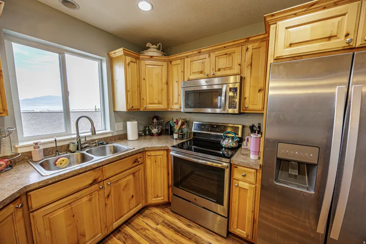 Kitchen featuring wood cabinetry, stainless steel appliances, a double basin sink, and wood-finish flooring