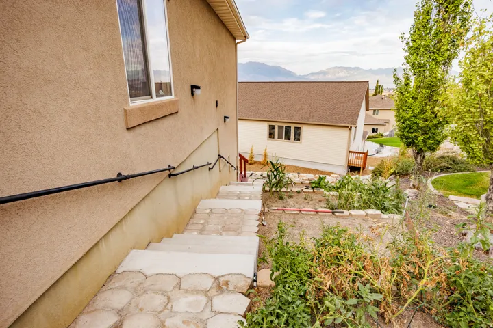 Stucco exterior with a ground-level window, exterior lighting fixtures, and a black handrail