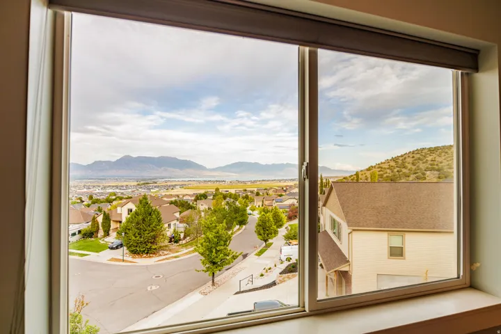 Expansive window offering a broad landscape with distant mountains, suburban residences, and a paved street