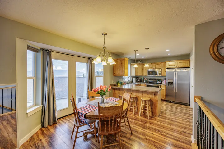 Wood-finish flooring throughout, kitchen with wood cabinetry, stainless steel appliances, and a breakfast bar