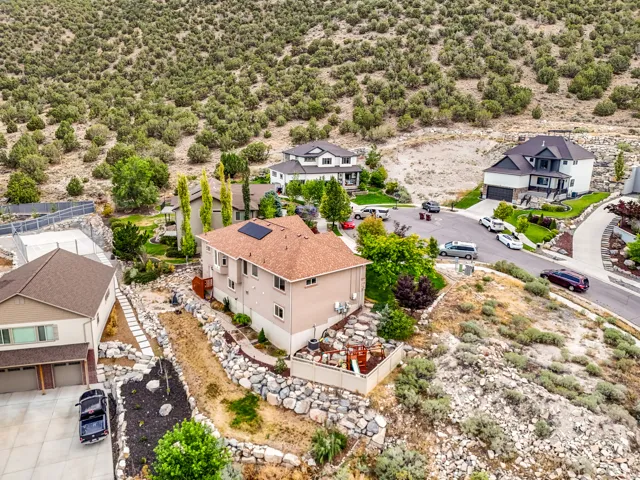 Terraced landscaping with stone retaining walls, mature trees, and a concrete driveway
