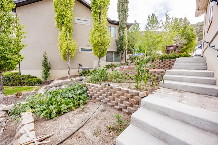 Multi-level concrete steps with a metal handrail, tiered retaining walls, and established landscaping