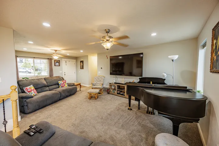 Spacious living area featuring neutral carpeting, recessed lighting, and multiple ceiling fans