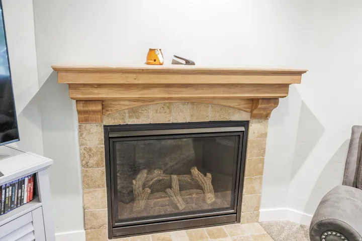 Fireplace featuring a light wood mantel, stone tile surround, and a black-framed glass screen