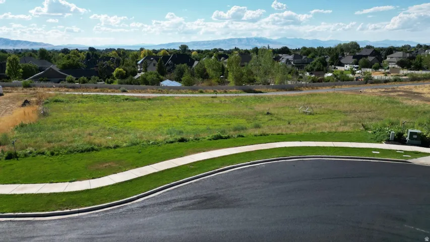 Expansive lot with a grass landscape, paved street, and concrete sidewalk