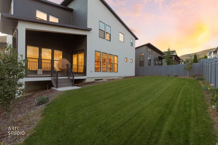 Expansive backyard with a manicured lawn, covered patio, and multi-pane windows