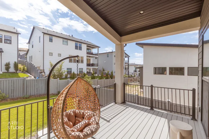 Covered outdoor deck with light-toned decking, dark metal railings, and a manicured lawn area