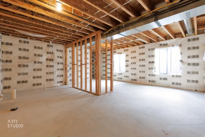Unfinished basement with exposed wood framing, concrete flooring, and multiple windows