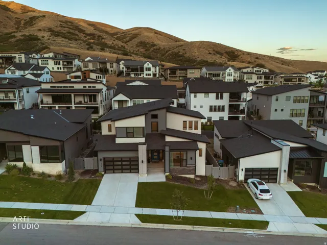 Modern architectural style featuring a multi-tone exterior, dark-toned roof, front-facing garage, concrete driveway, and manicured lawn