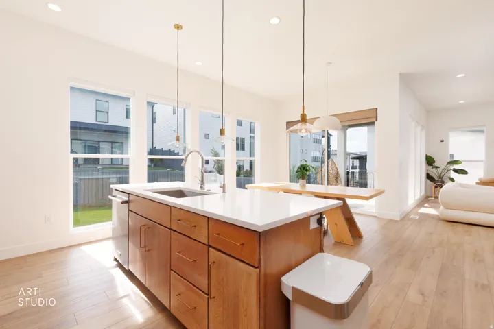 Open-concept kitchen with a central island, stainless steel sink, and wood-finish flooring