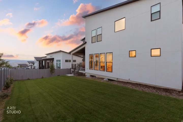 Modern exterior with expansive lawn area, multiple windows, and a privacy fence