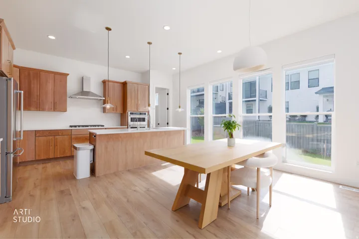 Open-concept kitchen and dining area featuring wood-finish flooring, warm wood cabinetry, a center island with countertop seating, and a stainless steel range hood
