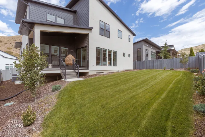 Expansive rear lawn, covered patio, and exterior siding in contrasting dark gray and white finishes