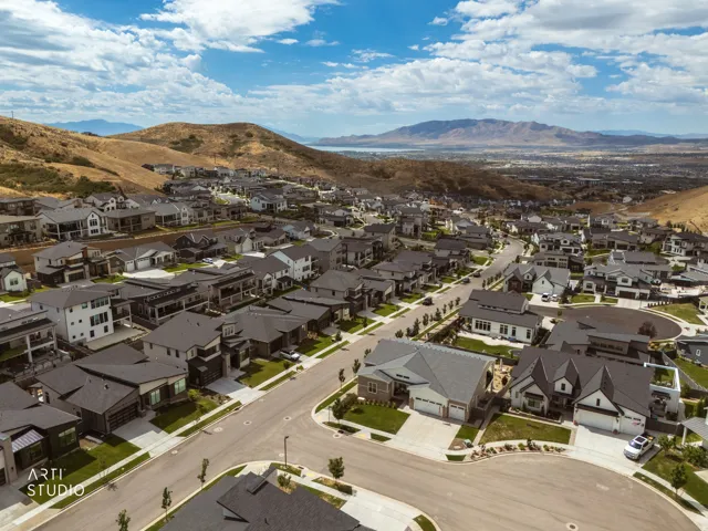 Sprawling neighborhood featuring varied architectural styles and extensive paved roads, set against a mountainous backdrop with distant water features