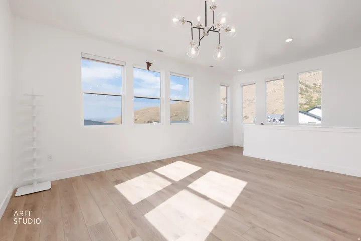 Expansive room featuring wood-finish flooring, a contemporary chandelier, multiple windows, recessed lighting, and a white interior wall finish