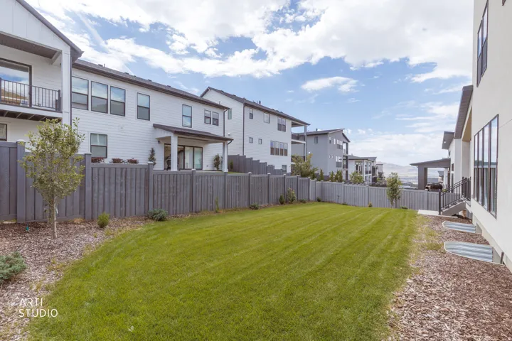 Expansive backyard featuring a manicured lawn, established privacy fencing, and wood-mulched planting areas