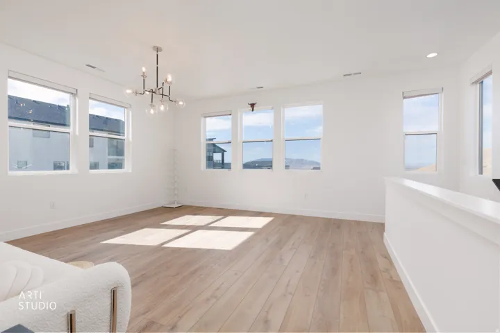 Expansive room featuring multiple windows, wood-finish flooring, a contemporary chandelier, and recessed lighting