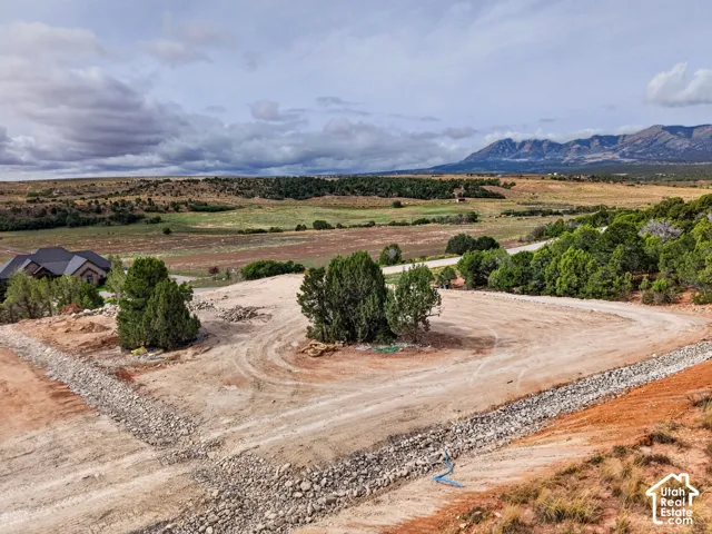 Expansive land parcel with surrounding natural landscape, distant mountain ranges, and established trees