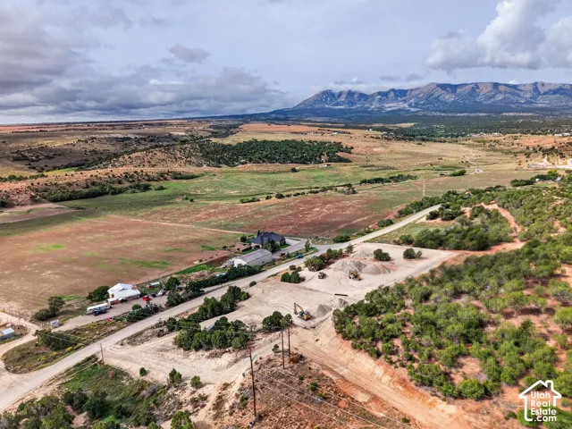 Expansive landscape with a distant mountain range, large fields, and scattered evergreen trees