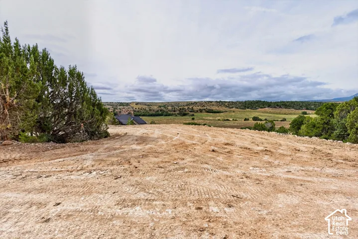 Expansive cleared lot with distant natural landscape and partial structure visible