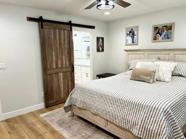 Barn door entry to an adjoining space, wood-finish flooring, recessed lighting, and a ceiling fan with integrated lighting
