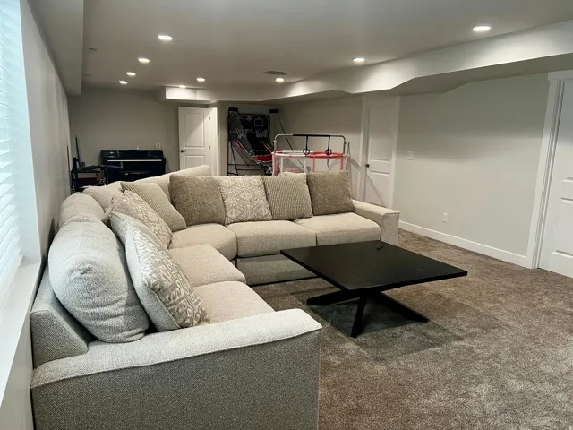 Carpeted living space with recessed lighting and a window featuring horizontal blinds