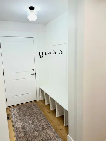 Entryway with wood-finish flooring, a white paneled door, and built-in white bench seating