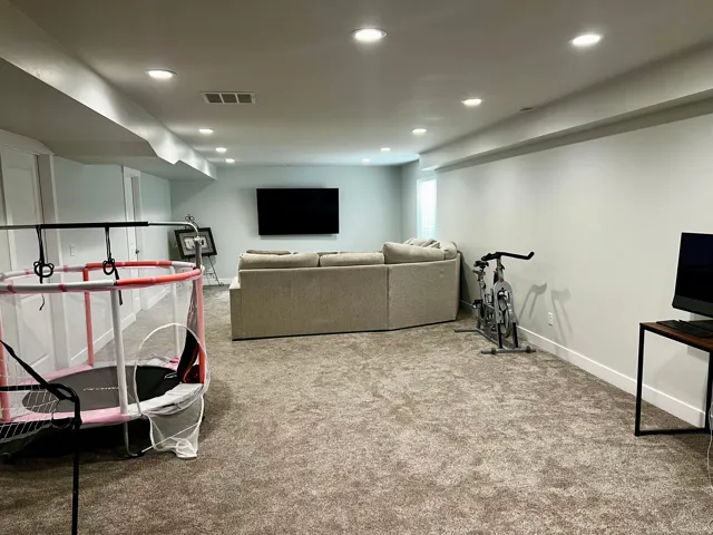 Spacious room with plush carpeting, recessed lighting, and crisp white baseboards
