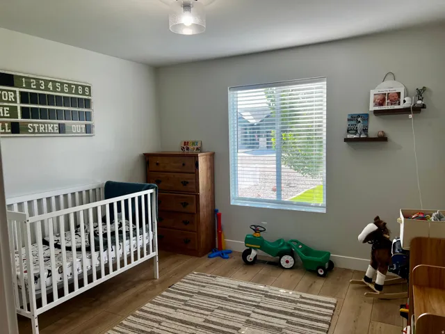Spacious room featuring wood-finish flooring, a contemporary flush mount ceiling light, and a large window with horizontal blinds