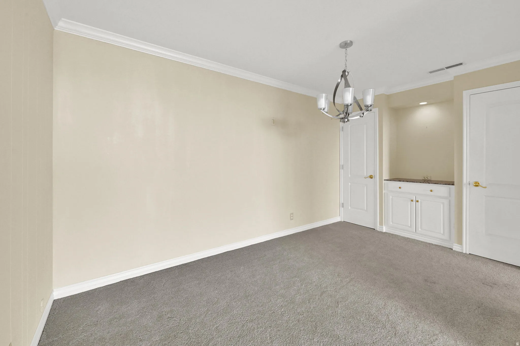 Recessed lighting, built-in cabinetry, polished countertop, and a contemporary chandelier