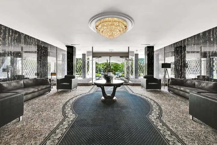 Ornate chandelier lighting, patterned wall finishes, decorative ceiling medallion, and large windows with decorative grilles