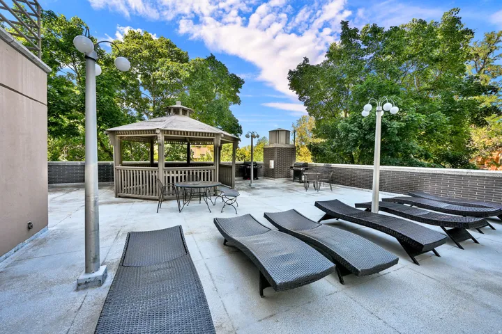 Rooftop patio featuring a gazebo, integrated grilling station, concrete flooring, and perimeter brick wall