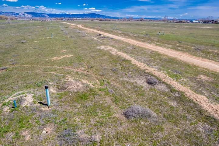 Expansive undeveloped land with a dirt access road and distant mountains