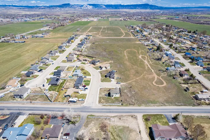 Expansive undeveloped land parcels with established residential development, multiple roadways, and distant mountain ranges