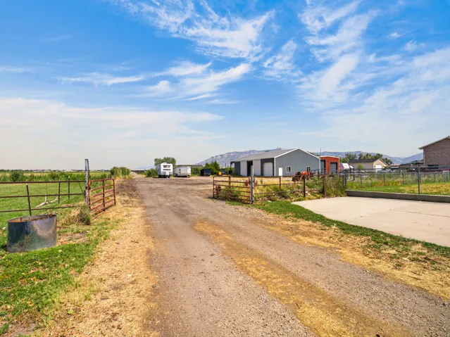Gravel driveway leading to a metal-sided utility building with a roll-up door