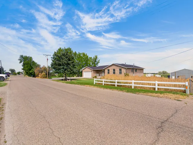 Brick exterior residence with an attached garage, white fencing, and a manicured lawn
